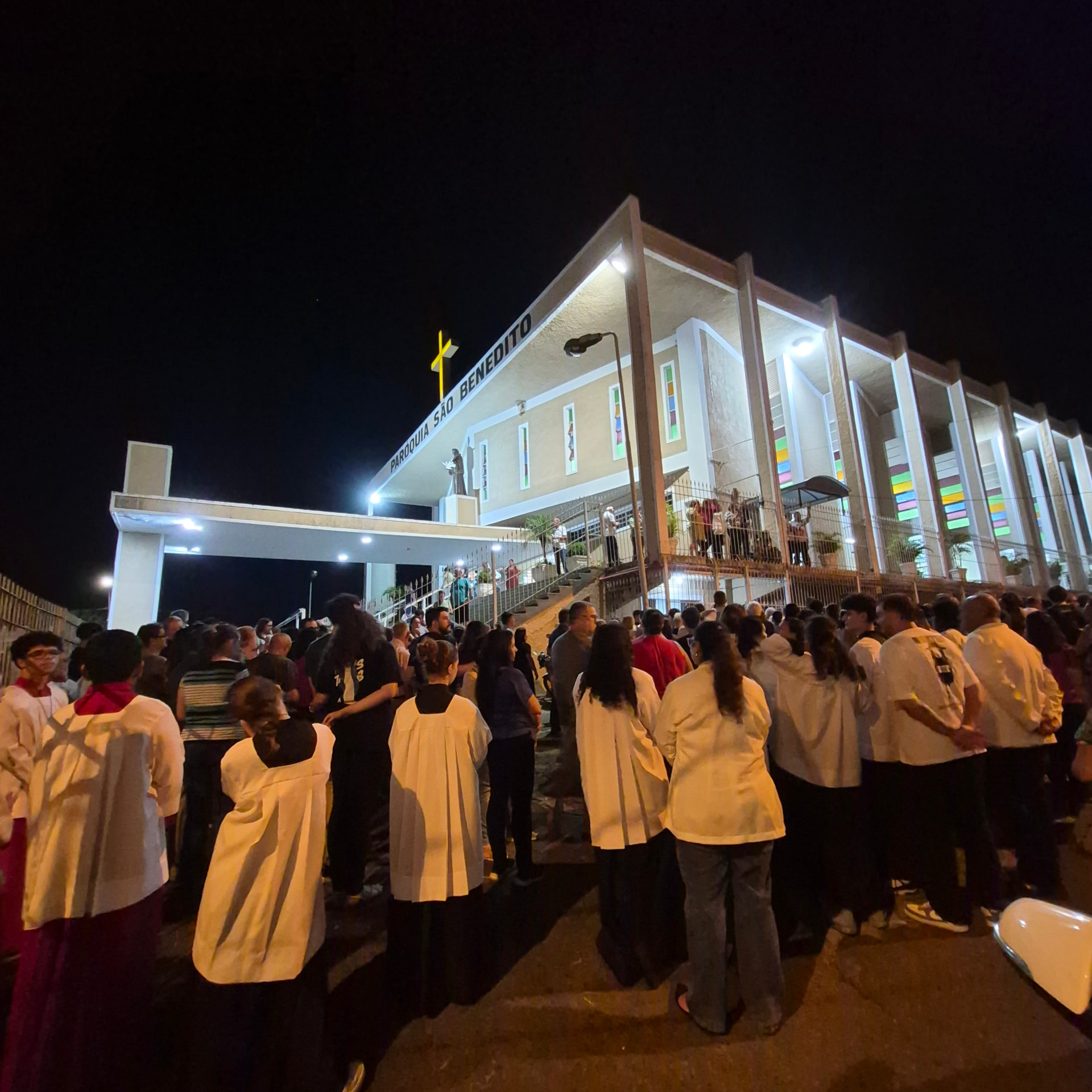 Fiéis reunidos em frente à igreja iluminada durante a Vigília