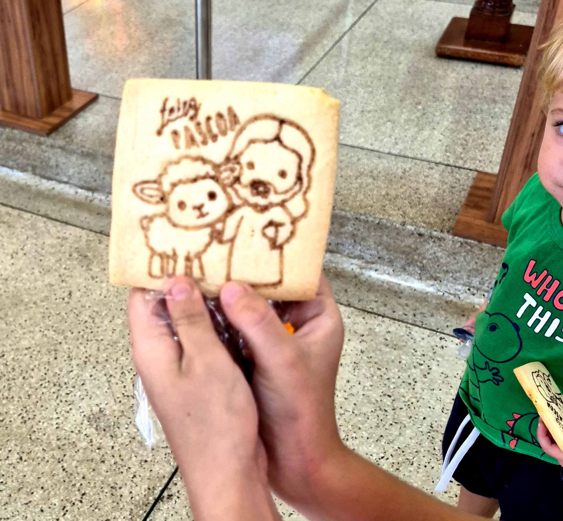 Criança segura biscoito decorado com 'Feliz Páscoa'