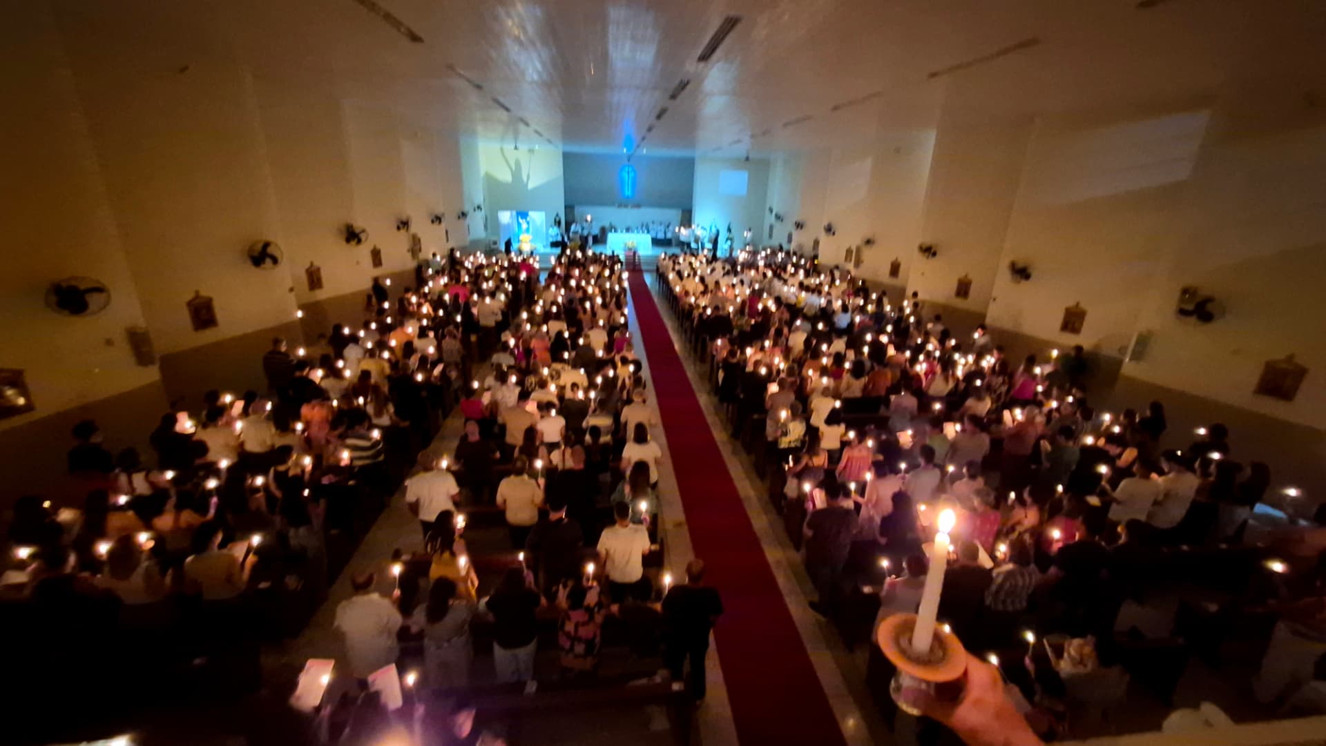 Vista da nave iluminada pelas velas dos fiéis